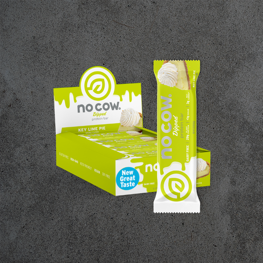 No Cow Key Lime Pie Dipped Protein Bar shown with its branded retail box and a single wrapped bar on a dark textured gray background.