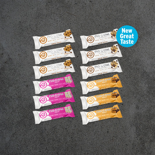 Assorted no cow protein bars on a dark surface with 'New Great Taste' label.